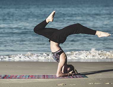 Девушка занимается йогой на коврике на берегу моря